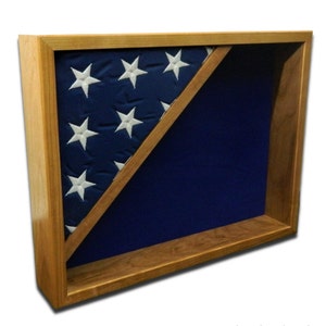 May include: A wooden flag display case with a blue velvet interior. The case is designed to hold a folded American flag, with the stars visible on the left side.