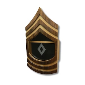 May include: A wooden shadow box in the shape of an Army E-7 Sergeant First Class rank insignia. The box is made of walnut and maple wood and has a black felt lining. The box is designed to hold a military medal or other small item.