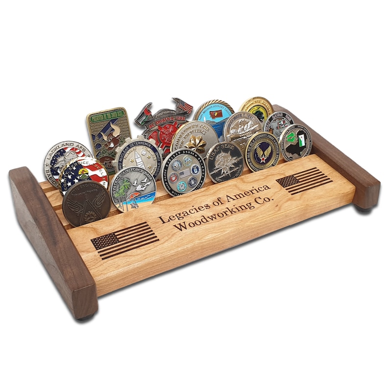 May include: A wooden coin display stand with an American flag design and the text "Legacies of America Woodworking Co.". The stand is filled with various challenge coins.