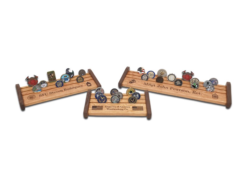 May include: Three wooden coin display stands with three rows of slots for holding challenge coins. The stands are personalized with names and the text "Legion of America Woodworking Co."