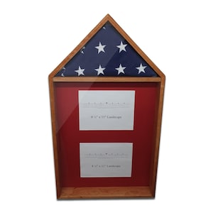 May include: A wooden flag display case with a glass front. The top section holds a folded American flag with stars and stripes. The lower section has a red background with two white paper inserts, each labeled "8 1/2" x 11" Landscape."