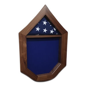 May include: A wooden flag display case with a blue felt lining and a folded American flag with white stars on a blue background in the top compartment.