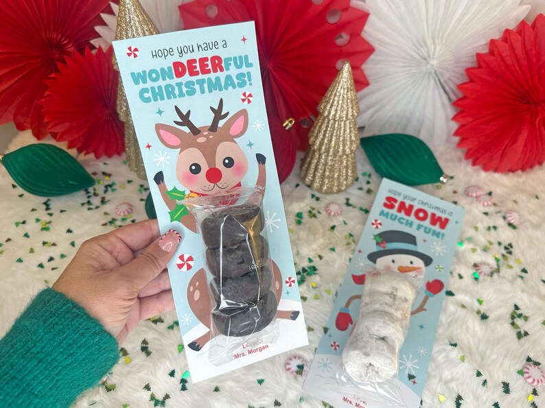 Op de afbeelding: Een kerstcadeau-label met een cartoon rendier en de tekst "Hope you have a WONDEERFUL CHRISTMAS!". Het label bevat een stapel donkergekleurde lekkernijen. Een tweede label toont een sneeuwpop.