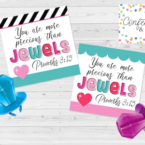 May include: Two pink and turquoise cards with the text "You are more precious than Jewels Proverbs 3:15" on each card. The cards are on a white wood background with a blue and purple ring pop on each card.