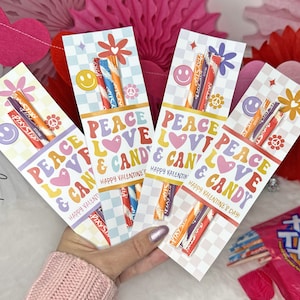May include: Four printable Valentine's Day gift tags with the text "Peace Love & Candy" in a retro font. Each tag features a colorful flower, a smiley face, and a checkered background. The tags are designed to hold candy sticks.