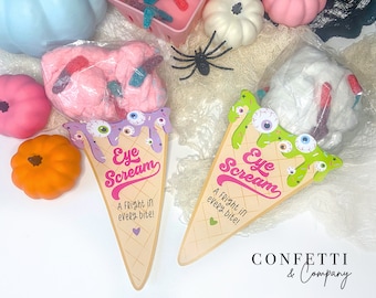 May include: Two decorative ice cream cone-shaped signs with the text "Eye Scream" and "A Fright in every bite!" are displayed. One cone has purple accents, the other green. Both have eyeball decorations. The cones are next to pink and white cotton candy.