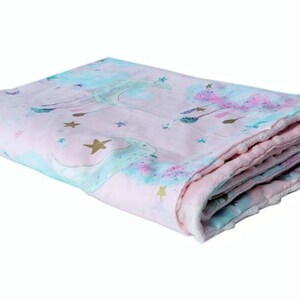 May include: A pink and blue baby blanket featuring a unicorn and stars design. The blanket is folded and has a soft, plush feel.