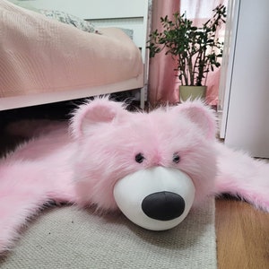 A close-up of the mascot's muzzle, a teddy bear-shaped rug. A sweet, shaggy carpet in the shape of a pink teddy bear. A floor mat for a little girl's room