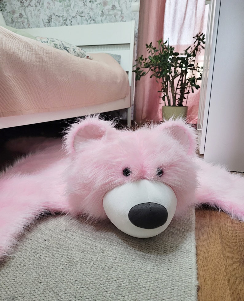 A close-up of the mascot's muzzle, a teddy bear-shaped rug. A sweet, shaggy carpet in the shape of a pink teddy bear. A floor mat for a little girl's room