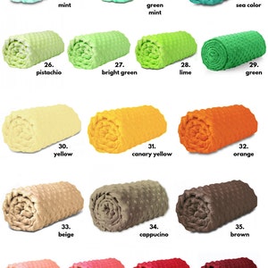 May include: A collection of 16 rolled up blankets in various colours, including mint, green, pistachio, yellow, beige, apricot, coral, red, and burgundy. Each blanket is labelled with a number and a colour name.