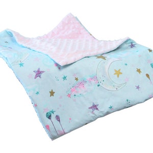 May include: A soft, blue and pink baby blanket with a moon and stars pattern. One side is a soft, plush fabric and the other side is a smooth cotton fabric.