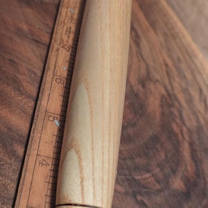Può includere: Un mattarello in legno chiaro con dettagli metallici color rame su entrambe le estremità. Il mattarello è cilindrico e ha una finitura liscia e lucida. Il mattarello è lungo circa 25 cm.