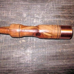 Puede incluir: Un mazo de madera y cobre con un mango de madera marrón y una cabeza de cobre.