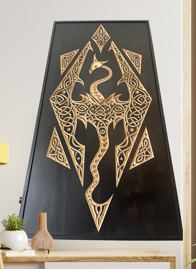 K&ouml;nnte beinhalten: Ein schwarzes Wandbild aus Holz mit einem goldenen Drachenmotiv, das in die Oberfl&auml;che geschnitzt ist. Der Drache ist in einem stilisierten, geometrischen Design mit filigranen Details gehalten. Das St&uuml;ck ist in einem schwarzen Holzrahmen gefasst.