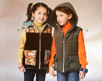 May include: A sewing pattern for children's vests, featuring two kids modeling the vests. The pattern is called "Kwik Sew" and the pattern number is K3975. The vests are in different styles, one with a colorful print and the other with a plaid pattern.