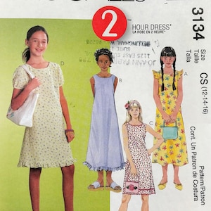 May include: McCall's sewing pattern for a 2-hour dress, size CS (12-14-16). The pattern includes three different dress styles: a short-sleeved dress with a floral print, a sleeveless dress with a solid blue color, and a sleeveless dress with a floral print. The pattern is for a child's dress.