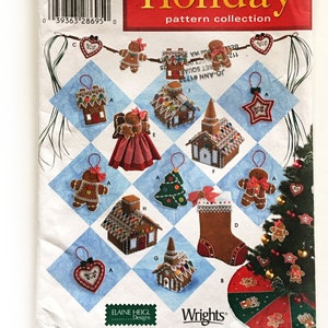 Könnte beinhalten: Eine Simplicity Holiday-Schnittmuster-Kollektion mit 10 verschiedenen Weihnachtsornamenten zum Nähen. Die Ornamente umfassen ein Lebkuchenhaus, einen Strumpf, einen Stern, einen Baum, einen Lebkuchenmann und einen Kranz. Das Schnittmuster stammt von Elaine Heigl Designs und ist bei Wrights erhältlich.