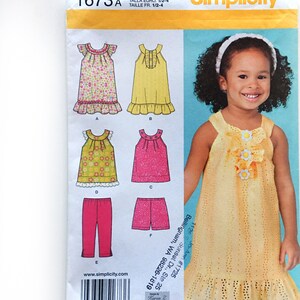 May include: A sewing pattern for a girl's dress and shorts. The pattern is for sizes 1/2-4. The pattern includes a yellow dress with a scalloped hem, a pink dress with a floral print, a green dress with a floral print, and pink shorts.