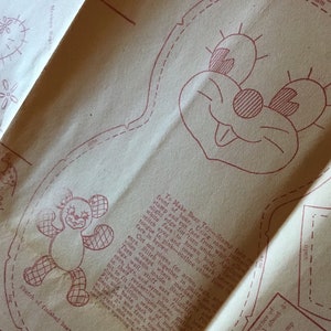 Pode incluir: Um padrão de artesanato vintage para fazer um brinquedo de urso de peluche. O padrão inclui instruções para cortar, costurar e encher o urso. O padrão também inclui um design para o rosto do urso, que apresenta uma boca sorridente, dois olhos e um nariz.