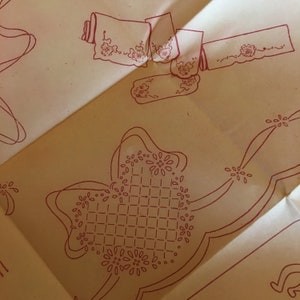 Puede incluir: Primer plano de un papel color crema con un diseño rojo de un patrón de cuadrícula con pequeñas formas de flores. El diseño tiene la forma de una mariposa.