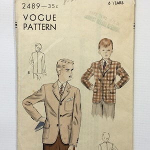 May include: Vintage Vogue sewing pattern for a boy's blazer. The pattern is for a 6-year-old and includes two different styles. The pattern is printed on a cream-colored paper with a brown and white illustration of a boy wearing a blazer.
