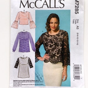 Puede incluir: Patrón de costura McCall's M7285. El patrón presenta ilustraciones de tops con varios estilos de mangas, incluyendo mangas acampanadas y detalles de encaje. El patrón incluye tallas A5 (6-8-10-12-14).