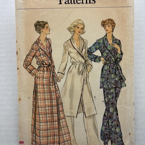 May include: A Vogue Patterns sewing pattern envelope, size 12, featuring illustrations of three robe and pyjama styles. The designs include a long plaid robe, a solid-coloured robe with matching trousers, and a floral print pyjama set with a jacket.