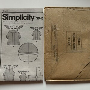 May include: A Simplicity sewing pattern for a baby costume. The pattern includes instructions for making a hooded robe, a floating pod, and a carrying cradle. The pattern number is S9432 and the size is OS (One Size).