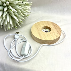 Könnte beinhalten: Ein Holzsockel mit einem runden Ausschnitt zum Ausstellen einer Kristallkugel. Der Sockel hat ein USB-Kabel und einen Inline-Schalter zum Ein- und Ausschalten der LED-Leuchten.