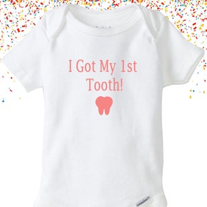 May include: White baby onesie with pink text that reads "I Got My 1st Tooth!" and a pink tooth graphic.