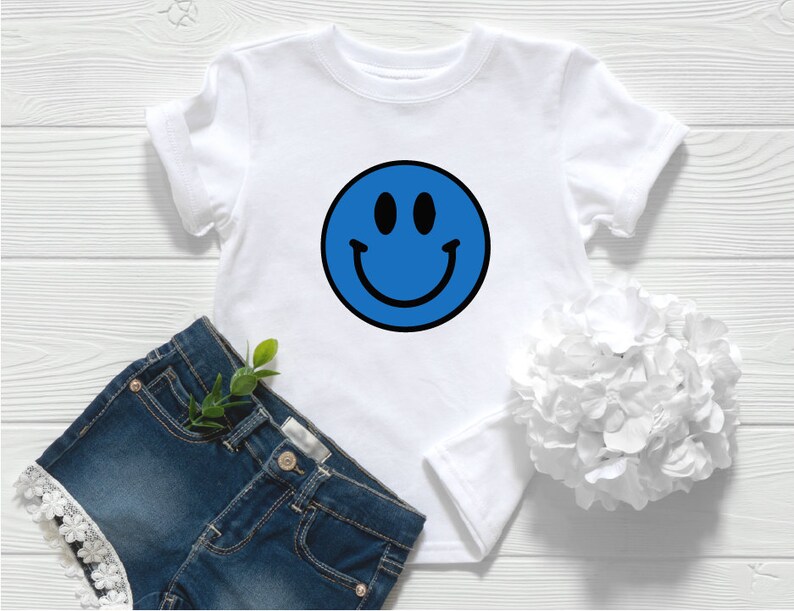 May include: White t-shirt with a blue smiley face graphic.