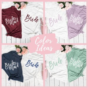 Puede incluir: Ideas de color para las camisas de las damas de honor. Las camisas son blancas con las palabras "Bride" y "Bridesmaid" en diferentes colores. Las camisas se muestran sobre un fondo de madera blanca.