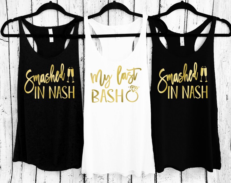 May include: Three tank tops with gold lettering. The first and third tank tops are black with the text "Smashed in Nash" and a pair of champagne flutes. The middle tank top is white with the text "My Last Bash" and a diamond ring.