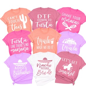 May include: A set of ten colorful t-shirts with various phrases and designs related to a fiesta theme. The shirts feature phrases like "Can't Touch This", "DTF Down to Fiesta", "Shake Your Maracas", "Fiesta Like There's No Manana", "Tequila Made Me Do It", "Tacos and Tequila", "Adios Bitchachos", "Nacho Average Bride", and "Let's Get Smashed".