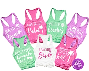 May include: Seven tank tops with various summer-themed phrases printed on them. The tank tops are in pink, green, white, and purple. The phrases include "Basic Beach", "Talk to the Palm", "Shell Yeah Beaches", "Suns Out Buns Out", "Resting Beach Face", "Beachin' Bride", and "Tropic Like It's Hot".