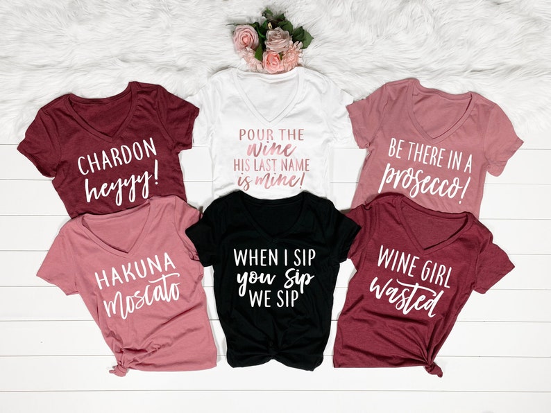 Puede incluir: Conjunto de seis camisetas con diferentes frases relacionadas con el vino. Las camisetas son de diferentes colores, incluyendo blanco, negro, rosa y granate. Las frases en las camisetas incluyen "Chardon heyyy!" "Hakuna Moscato" "&iexcl;Sirve el vino, su apellido es m&iacute;o!" "Cuando yo bebo, t&uacute; bebes, bebemos" "&iexcl;Est&eacute; ah&iacute; en un prosecco!" y "Chica del vino desperdiciada."
