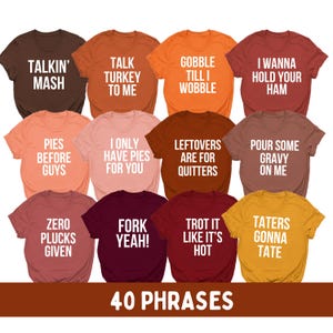 Puede incluir: Una colección de doce camisetas de manga corta en varios colores otoñales, cada una con texto blanco con frases humorísticas sobre el Día de Acción de Gracias como Talkin' Mash y Gobble Till I Wobble, dispuestas en cuadrícula.