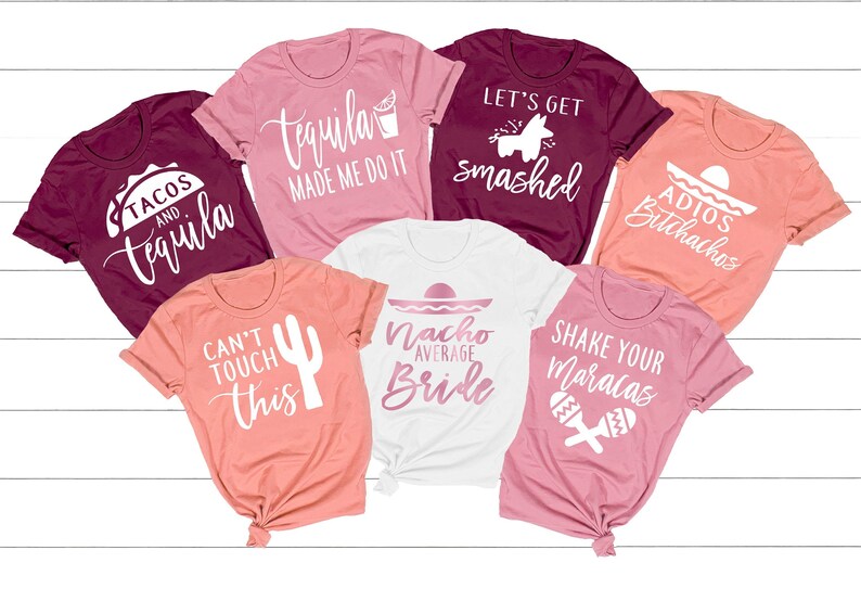 May include: Seven different t-shirts with various designs and text related to a bachelorette party. The shirts are in shades of pink, coral, and burgundy. The text on the shirts includes "Tacos and Tequila", "Tequila Made Me Do It", "Let's Get Smashed", "Adios Bitchachos", "Can't Touch This", "Nacho Average Bride", and "Shake Your Maracas".