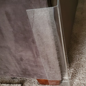 Puede incluir: Un protector de esquinas para muebles en forma de L hecho de acr&iacute;lico transparente. Esta pieza de pl&aacute;stico r&iacute;gido e incoloro presenta un &aacute;ngulo recto, proporcionando una barrera protectora lisa que se ajusta al borde de un mueble.