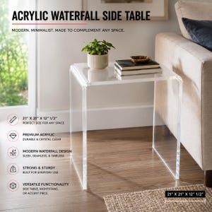 May include: A clear acrylic waterfall side table with a seamless, U-shaped design. The table measures 21 inches by 21 inches by 12.5 inches. It is shown with a small potted green plant and two stacked books placed on its flat top surface.