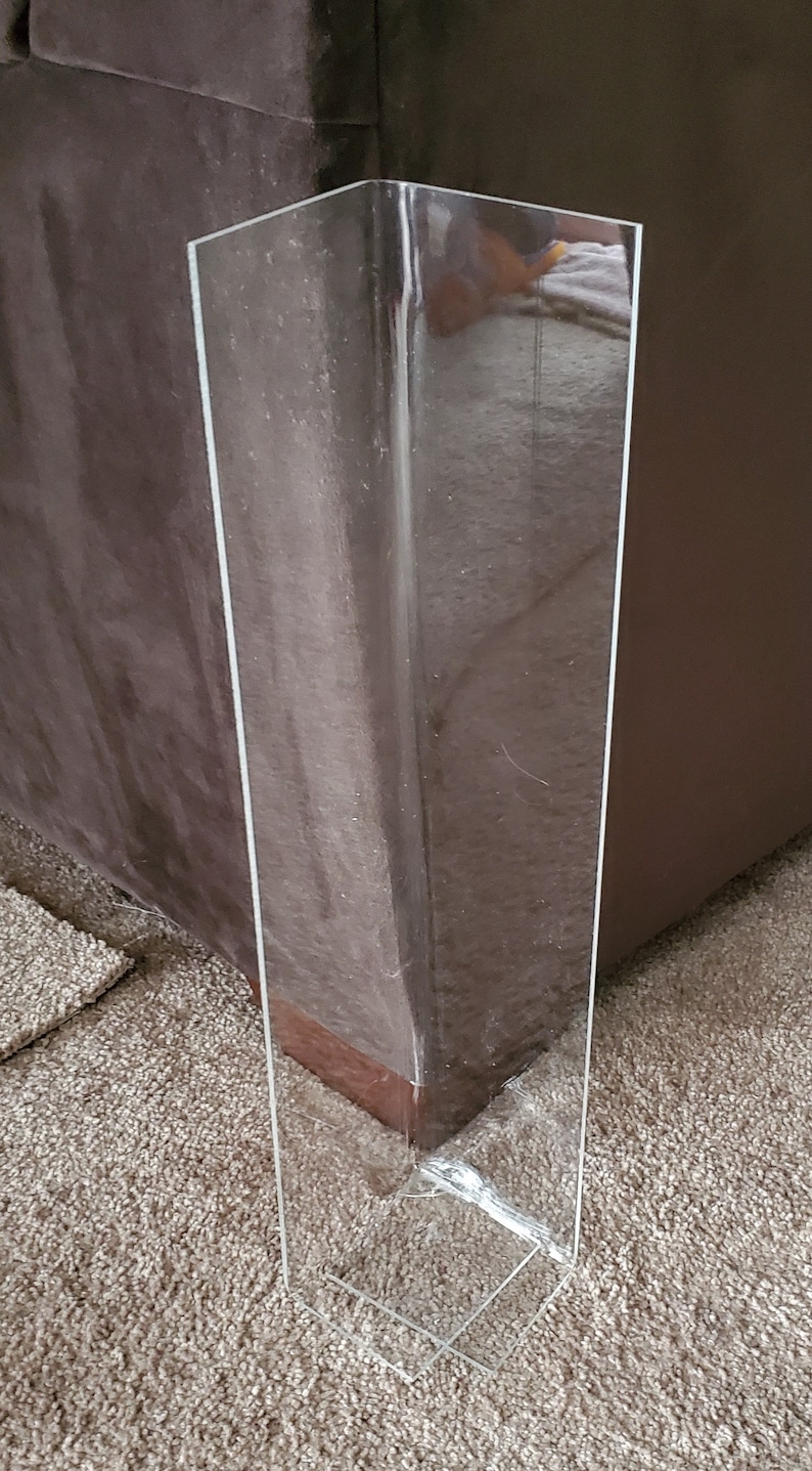 Puede incluir: Un protector de esquinas de acr&iacute;lico transparente, alto y r&iacute;gido, con un perfil en L de &aacute;ngulo recto. Este dise&ntilde;o vertical est&aacute; pensado para proteger los bordes de las paredes contra impactos y desgaste, manteniendo una apariencia discreta.