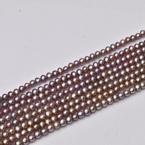 May include: A strand of iridescent purple freshwater pearls. The pearls are round and smooth, and they have a subtle shimmer.