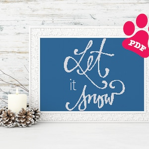 Peut inclure: Une image encadrée de blanc avec un fond bleu et le texte "Let it snow" en lettres blanches en cursive. Une bougie blanche et des pommes de pin sont au premier plan.