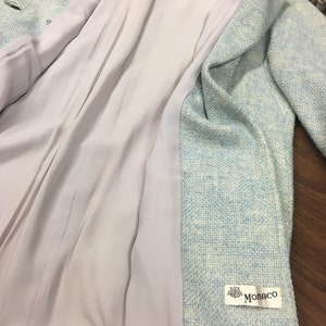 May include: A light blue blazer with a white and light blue patterned design. The blazer has a white lining and a label that says "Monaco".
