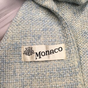 May include: A close-up of a light blue woven fabric with a white label that says "Monaco" with a crest.