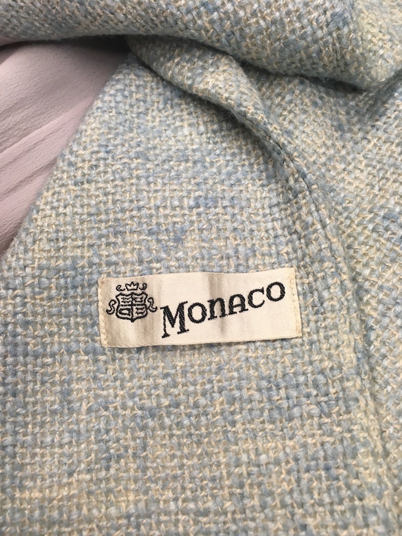 May include: A close-up of a light blue woven fabric with a white label that says "Monaco" with a crest.