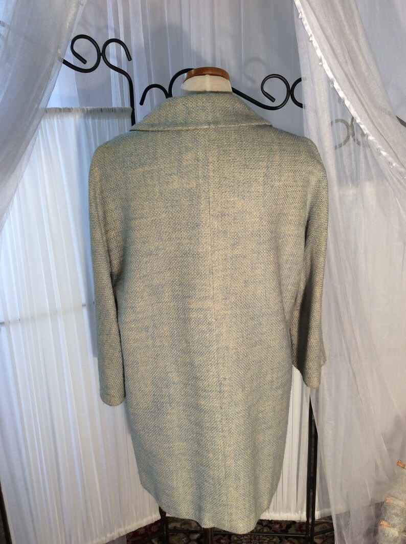 May include: A light blue blazer with a textured woven fabric. The blazer has a classic collar and long sleeves.