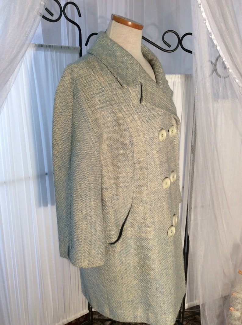 May include: A light blue blazer with a white and light blue patterned design. The blazer has a double breasted closure with white buttons and a single pocket on the left side.