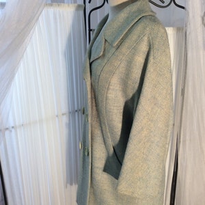 May include: A light blue tweed jacket with a double breasted closure and a large collar. The jacket has a subtle pattern of white and light blue.