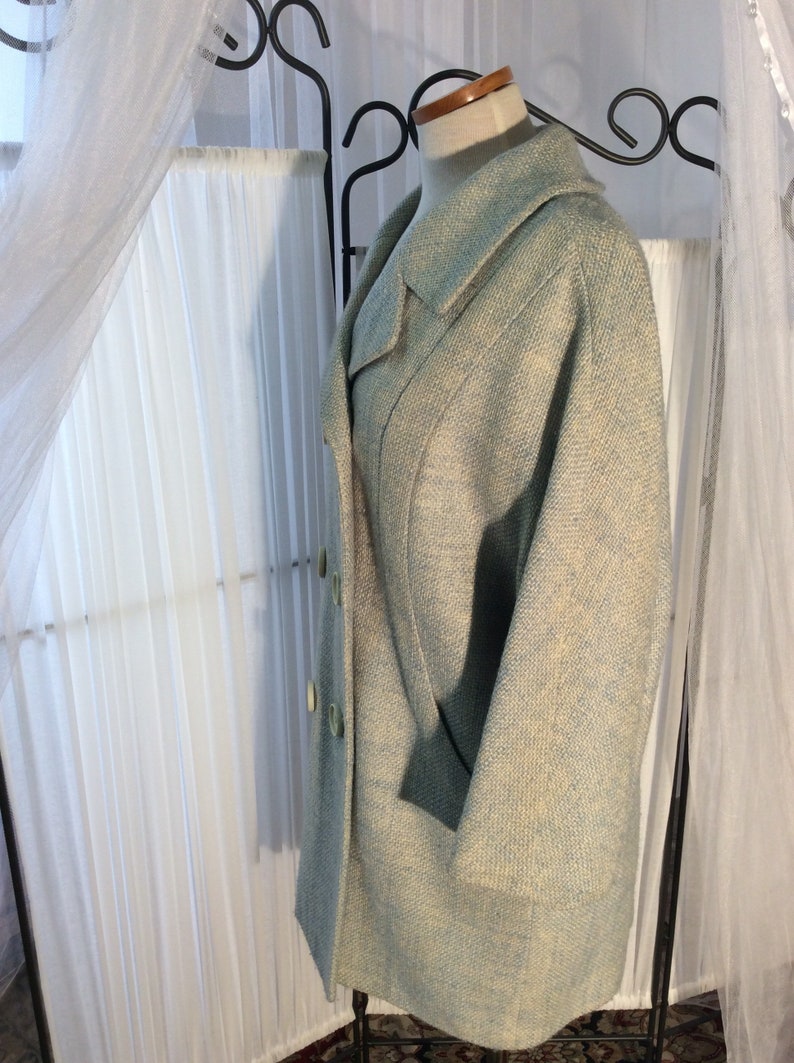 May include: A light blue tweed jacket with a double breasted closure and a large collar. The jacket has a subtle pattern of white and light blue.